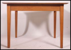 A 20th century school table in oak raised on squared legs with fitted frieze and square table top