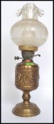 An ornate brass oil lamp having roses in repose to the body, original shade and glass flue.