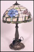 A Tiffany style lamp, having leaded coloured glass shade, raised on a Art Nouveau style base.