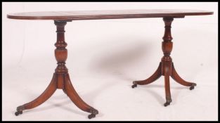 A reproduction 20th century tea table, raised on  twin pedestal reeded tripod legs,