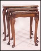 A set of three Walnut quarter panel vaneered nest of tables, all retaining inset glass panels,