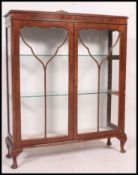 A 1930's glazed display cabinet, having glass shelves to the interior raised on cabriole legs.