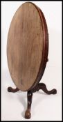 A Victorian mahogany circular tilt top breakfast table being raised on shaped scroll tripod support