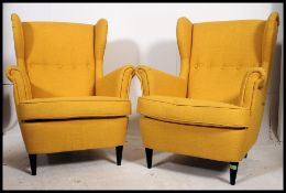 A stunning pair of contemporary Ikea Strandmon armchairs raised on tapered supports with yellow