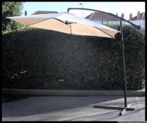 A contemporary large garden extending parasol and stand. The parasol in a beige canvas fabric.