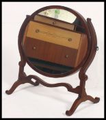 An Edwardian oval mahogany toilet swing mirror together with a mahogany fire screen with shelf to