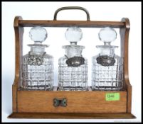 An early 20th century tantalus with oak frame, 3 glass decanters, each with stoppers.