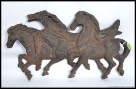 A large early 20th century / mid century cast iron wall plaque in the form of four wild horses.