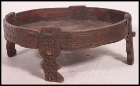 A 20th century Indian cartwheel opium table. Raised on stile legs with scratch carved design.