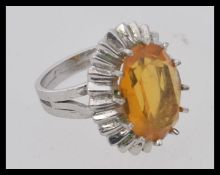 A large Citrine and white metal ladies cocktail ring set on sunburst oval mount and plain shank.