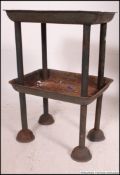 An Industrial 20th century metal tote stand having twin tray style tiers being raised on tubular
