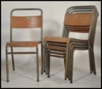 A stack of vintage mid century tubular metal and ply wood Industrial stacking chairs bearing
