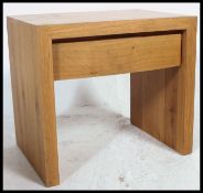 A contemporary chunky oak side table of square form with drawer raised on squared legs