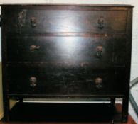 A 1930's oak chest of drawers being raised on squared legs with a bank of drawers having original