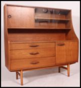 A 1970's retro teak Danish influence sideboard having a series of cupboards and drawers raised on