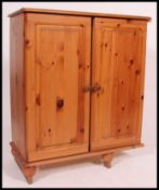 A contemporary pine side cabinet. Twin full length doors with shelved interior and flared top above.