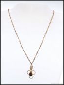 A 9ct gold necklace with gold and agate stone set pendant of filigree form. Stamped 9ct.