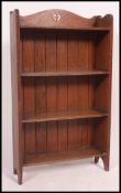 An early 20th century Arts & Crafts oak open window bookcase cabinet having fixed shelves with a