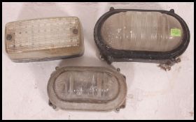 A collection of three vintage mid 20th century industrial bulk head lights to include square shaped,