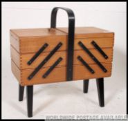 A vintage retro 1950's sewing box with cantilever sections and ebonised legs and handle.