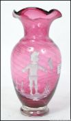 A 20th century Mary Gregory style cranberry vase with etched decoration of a child.