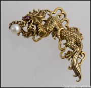 A stunning Chinese gilded silver dragon brooch having freshwater pearl and ruby stone set eyes.