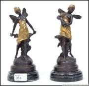 A pair of Art Nouveau bronze and brass fairy figurines being raised on marble socle plinths.