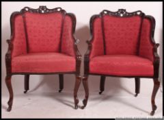 A pair of Edwardian mahogany show wood salon armchairs raised on cabriole legs with rococo carved