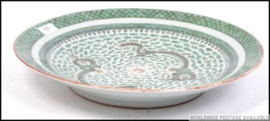 A 1930's Chinese celedon Chinese large charger with twin dragons having green ground and geometric