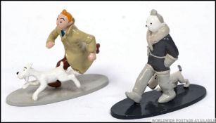 2 decorative die cast Tin Tin figurines being enamel painted by Herge, each on flat base plinth.