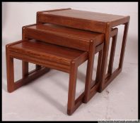 A vintage mid century teak / rosewood nest of tables being raised on squared legs with graduating