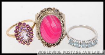 A collection of three silver costume jewellery dress rings to include an oversized cut pink marble