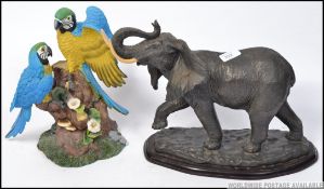 A highly detailed resin parrot figurine group perched atop a tree trunk on resin base set in