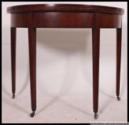 A Georgian mahogany inlaid demi lune card table being raised on tapered squared legs with flip over