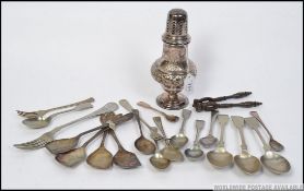 A decorative silver plated sugar shaker in relief along with flatware,