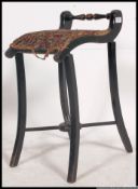 A Victorian ebonised piano stool of tall form with shaped legs and upholstered seat with handle
