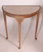 A 1950's walnut queen anne revival demi lune console hall table raised on cabriole legs and glass