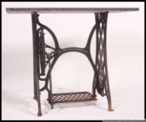 A vintage early 20th century cast iron treadle sewing machine base having a later applied marble