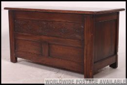 A 1950's Jacobean revival oak coffer blanket box chest with carved details to centre having flared