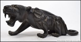 A 20th century Chinese carved wooden model of a snarling tiger on naturalistic base.