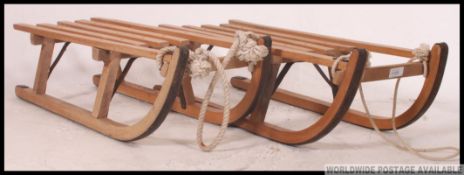 A pair of vintage mid century wooden sledges having slatted seats and ropes in excellent condition.