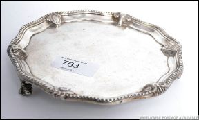 A Victorian silver hallmarked card tray being raised on claw and ball feet ( two missing ) by