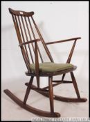 An dark Ercol beech and elm rocking windsor chair with spindle back being raised on turned legs