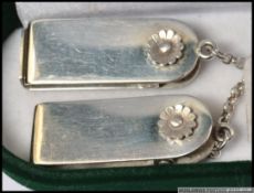 A cased pair of silver hallmarked scarf clips connected by a silver chain,