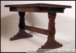 A 20th century dark oak draw leaf refectory dining table being raised on lyre shaped supports with