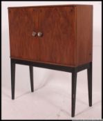 A retro 1970's teak Danish influence side cabinet being raised on ebonised tapered supports