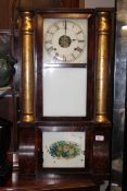 A 19th century American gingerbread wall clock with gilt painted columns to the mahogany case with