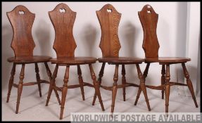 A set of four vintage oak waisted panel back chairs with circular seat pad raised on turned legs