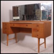 A retro 1970's Ernest Gomme for G-Plan light oak dressing table raised on tapered legs with a