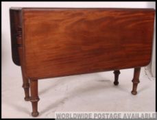 A 19th century Georgian mahogany drop leaf / gate leg dining table being raised on turned legs with